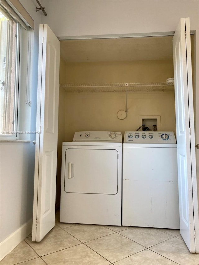 laundry room with laundry area, baseboards, washing machine and clothes dryer, and light tile patterned floors