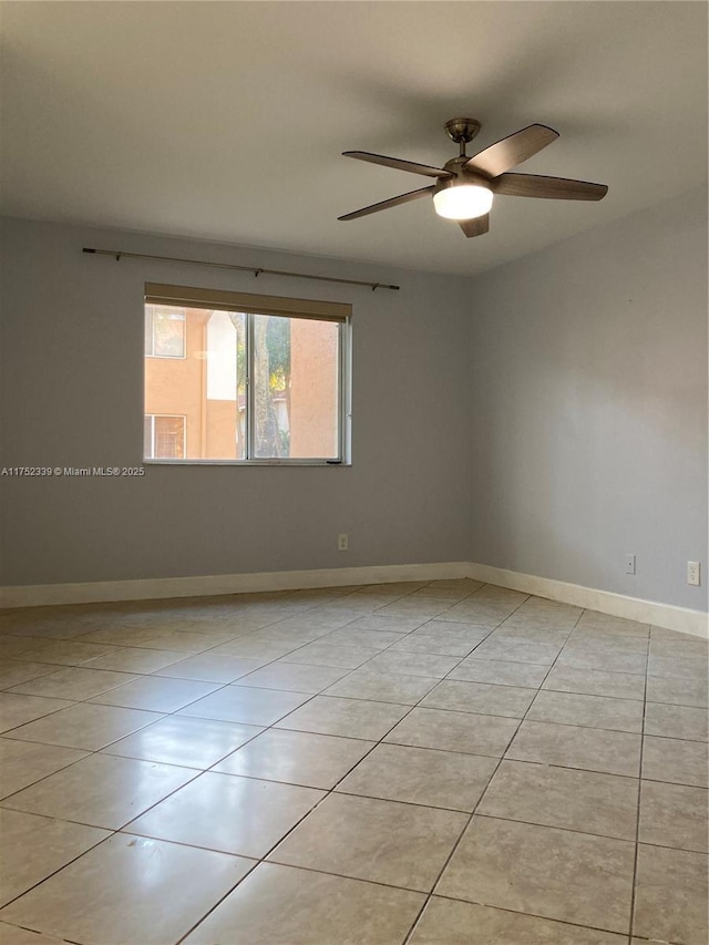 empty room with ceiling fan, baseboards, and light tile patterned flooring