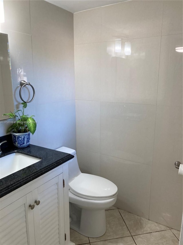 half bathroom with vanity, tile patterned flooring, toilet, and tile walls