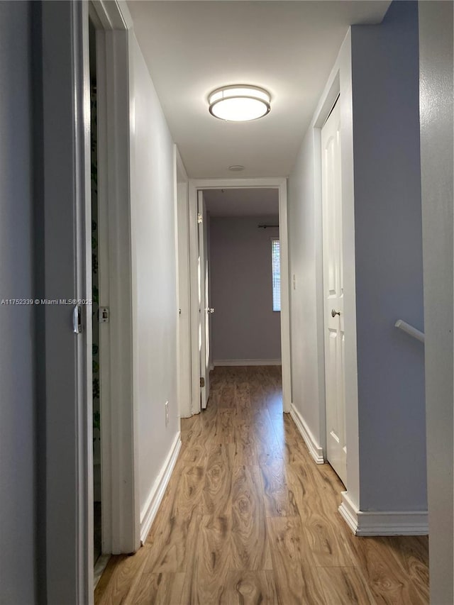 corridor with baseboards and light wood-style floors