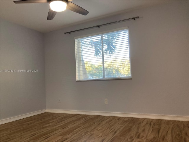 empty room with dark wood-style floors, baseboards, and a ceiling fan