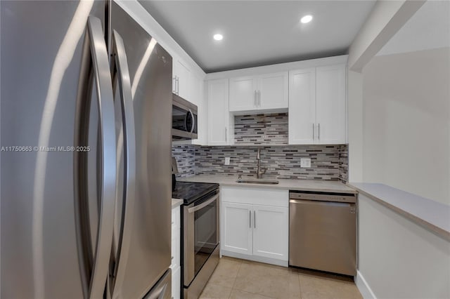 kitchen with stainless steel appliances, light countertops, white cabinets, a sink, and light tile patterned flooring