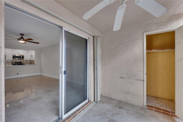 interior space featuring a ceiling fan and a textured wall