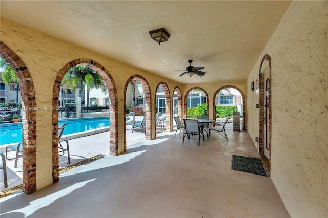 view of patio featuring a community pool, a ceiling fan, and outdoor dining space