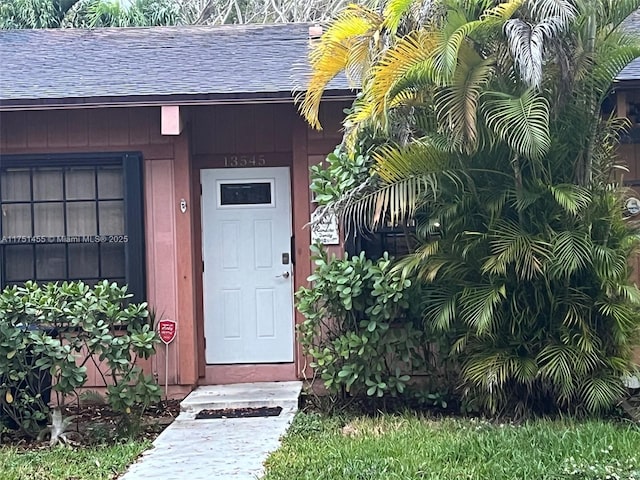 entrance to property featuring roof with shingles