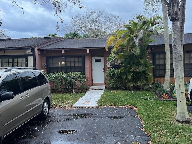 view of front facade with a shingled roof and a front yard