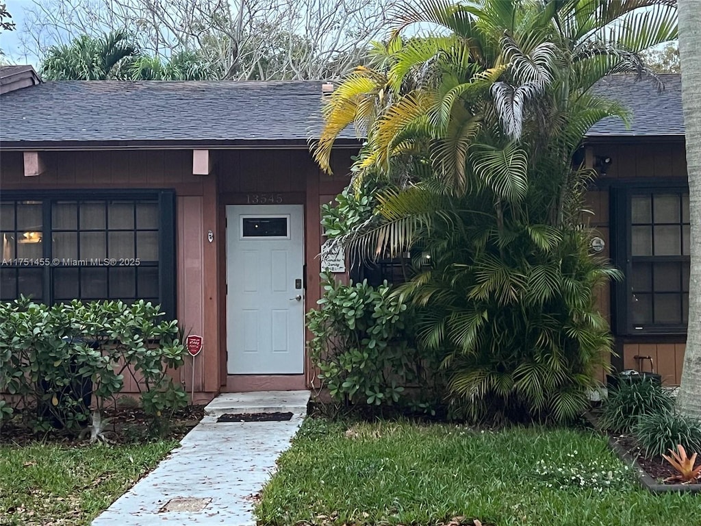 doorway to property featuring roof with shingles