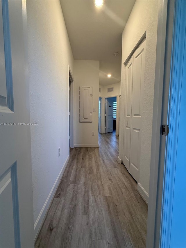 hall featuring visible vents, baseboards, and wood finished floors