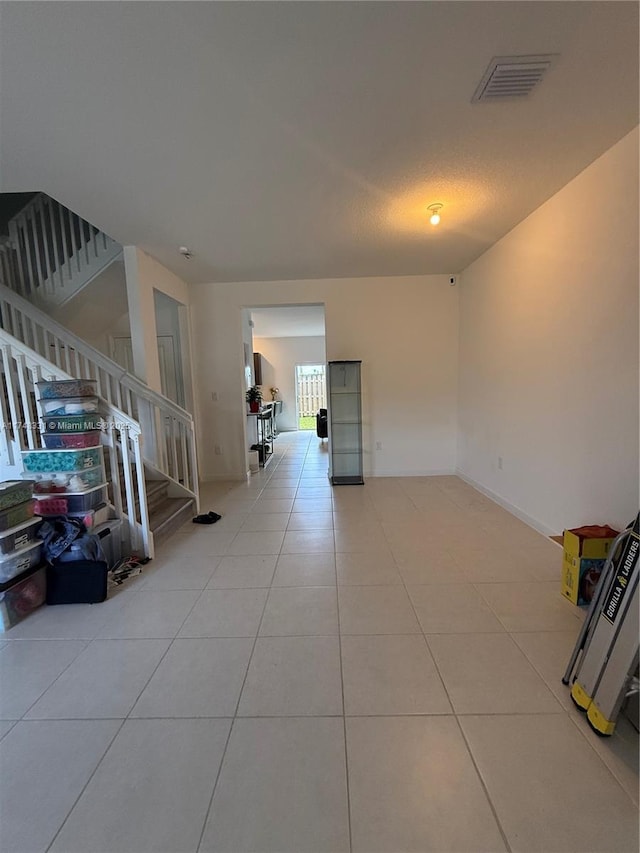 spare room with light tile patterned floors, stairway, and visible vents