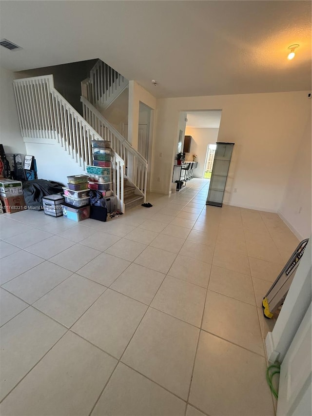 living area with light tile patterned floors, stairway, and visible vents