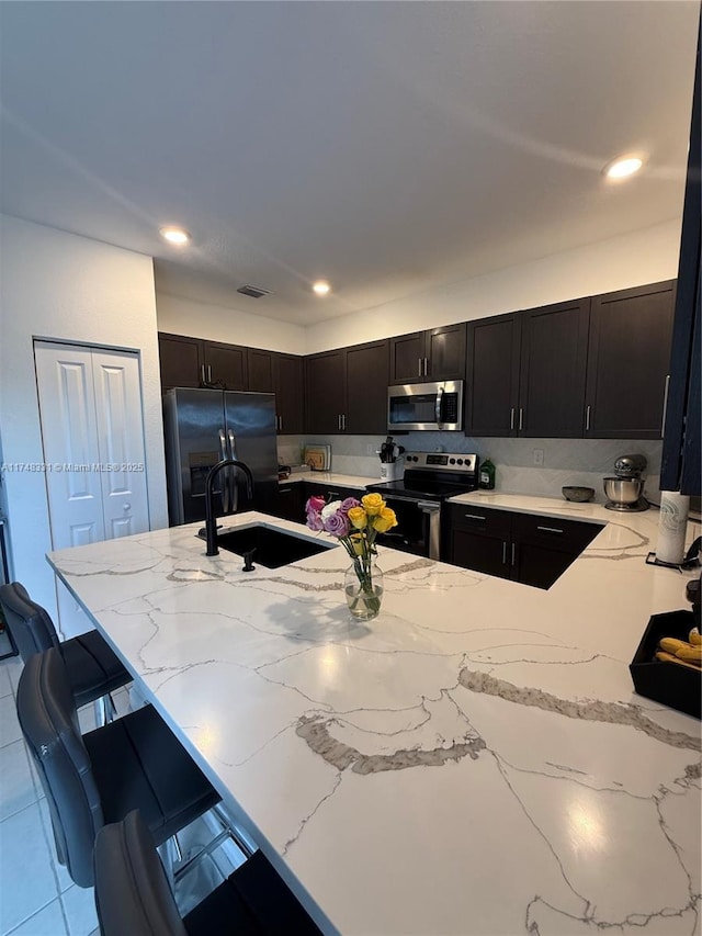 kitchen featuring visible vents, a breakfast bar, stainless steel appliances, a sink, and recessed lighting