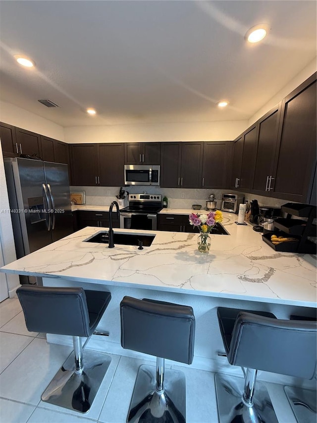 kitchen featuring stainless steel appliances, a breakfast bar area, a sink, and visible vents