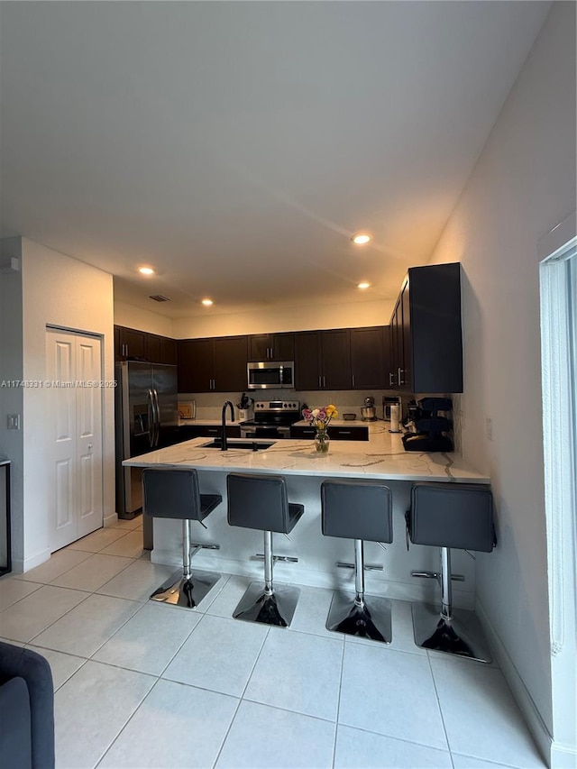 kitchen featuring a peninsula, light tile patterned floors, stainless steel appliances, and light countertops