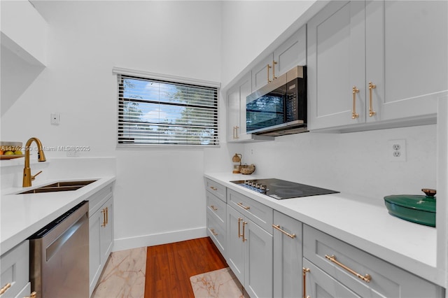kitchen with light countertops, stainless steel appliances, baseboards, and a sink