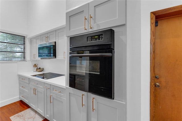 kitchen featuring light countertops, baseboards, dark wood finished floors, and black appliances