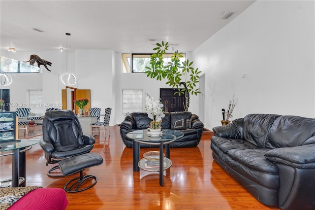 living room featuring visible vents, a towering ceiling, and wood finished floors