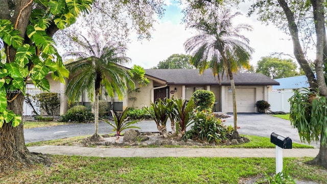 view of front of house featuring a garage, aphalt driveway, stucco siding, and fence
