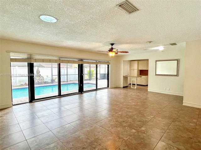 unfurnished room featuring a ceiling fan, visible vents, a textured ceiling, and baseboards