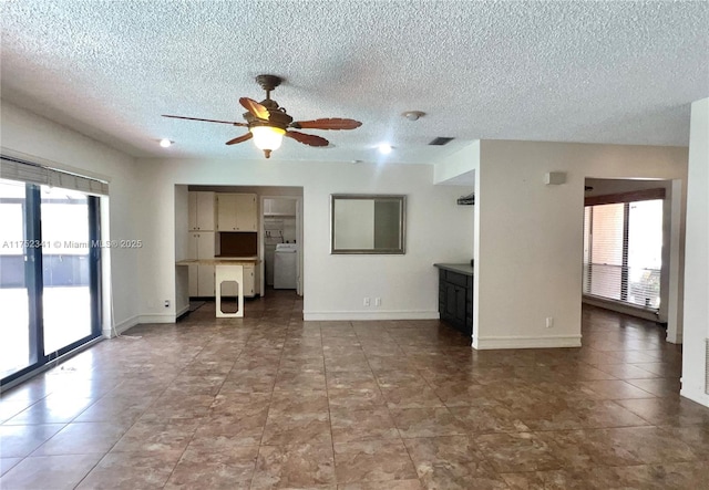 unfurnished living room with a textured ceiling, baseboards, a ceiling fan, and washer / dryer