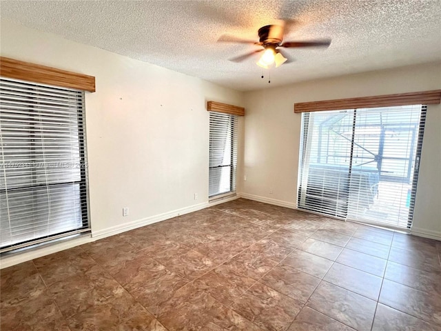 empty room featuring ceiling fan, a textured ceiling, and baseboards