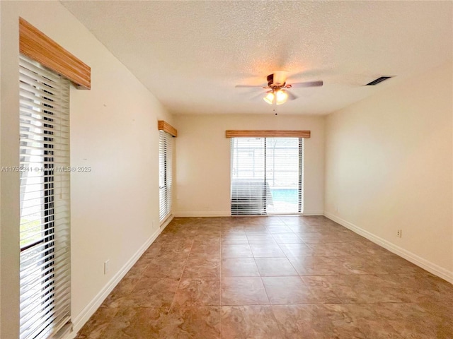 unfurnished room featuring visible vents, ceiling fan, a textured ceiling, baseboards, and tile patterned floors