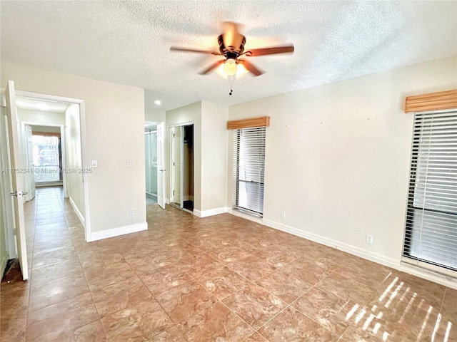 empty room featuring a ceiling fan, baseboards, and a textured ceiling