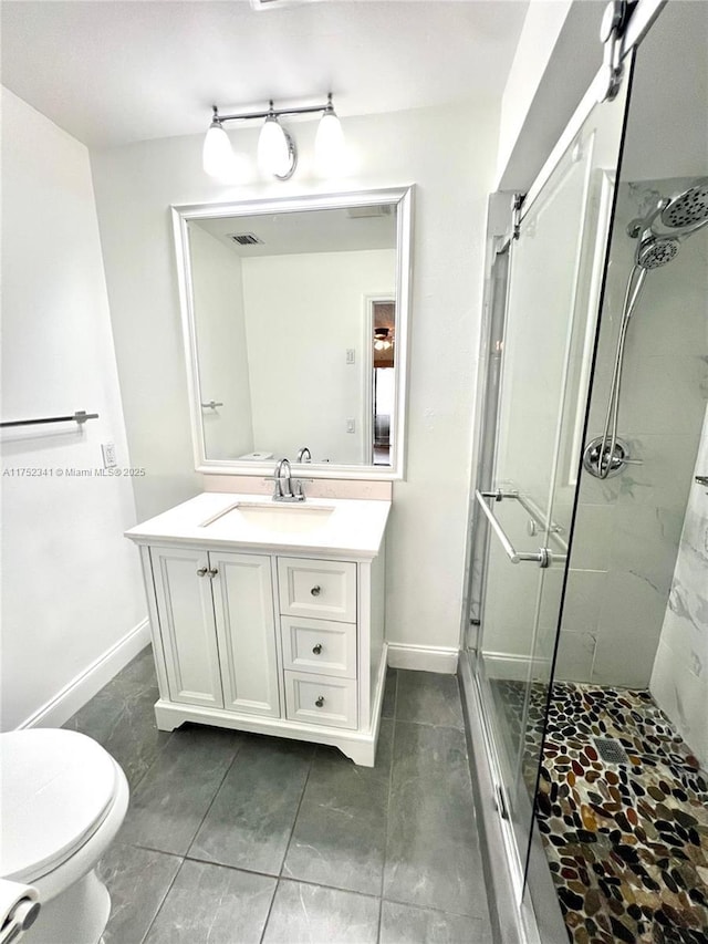 full bathroom featuring toilet, vanity, visible vents, baseboards, and a stall shower