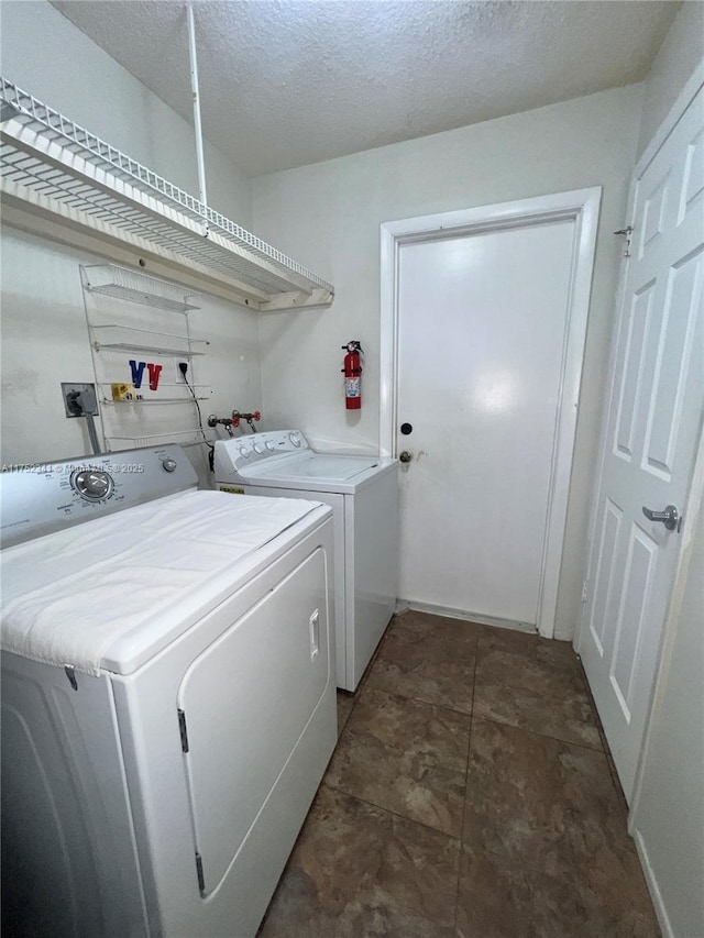 laundry area featuring washing machine and clothes dryer, laundry area, and a textured ceiling