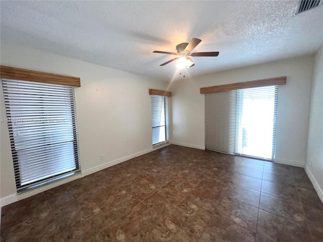 tiled empty room with a textured ceiling, baseboards, a ceiling fan, and visible vents