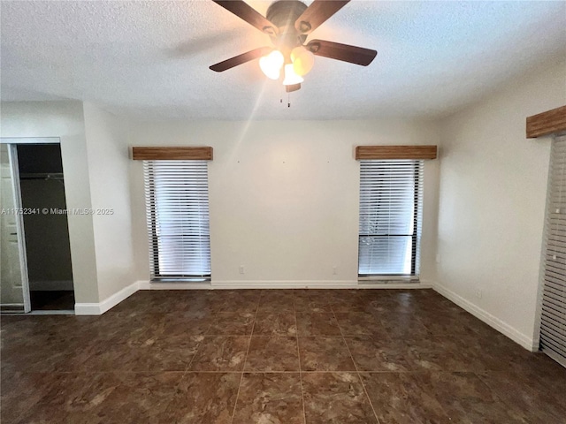 tiled empty room with a wealth of natural light, a textured ceiling, and a ceiling fan