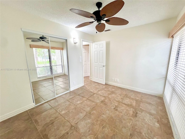 unfurnished bedroom with a textured ceiling, ceiling fan, visible vents, baseboards, and a closet