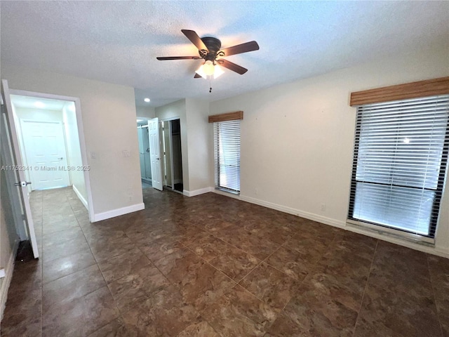 unfurnished room with dark tile patterned floors, a textured ceiling, baseboards, and ceiling fan