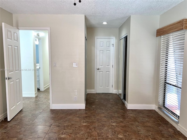interior space featuring baseboards, a textured ceiling, and a closet