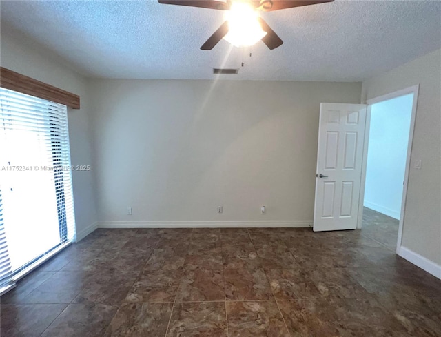 spare room featuring a textured ceiling, ceiling fan, and plenty of natural light