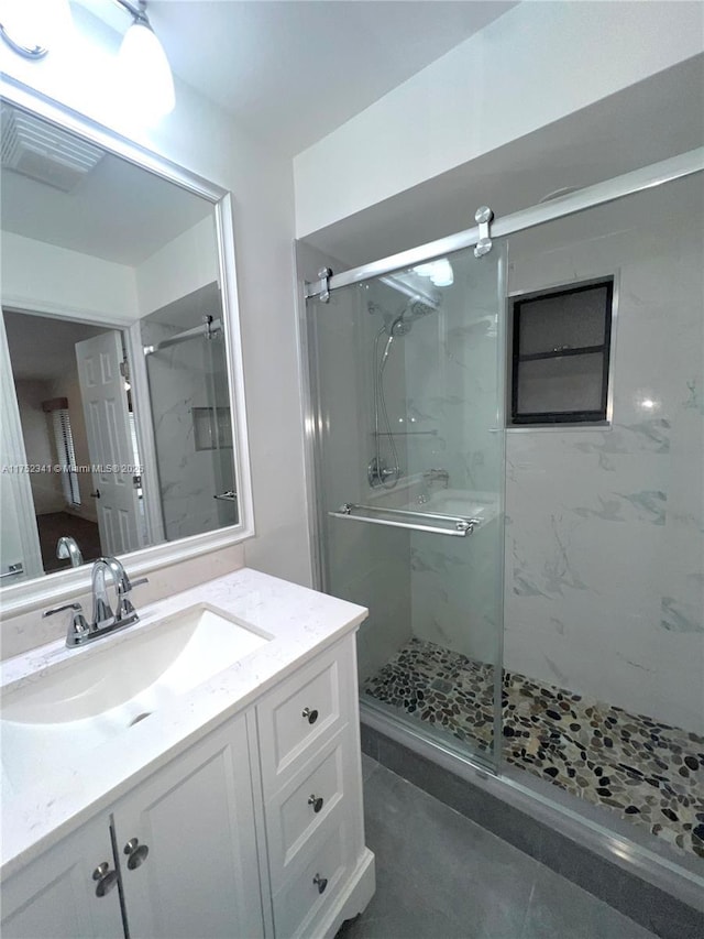 bathroom with a marble finish shower, visible vents, and vanity
