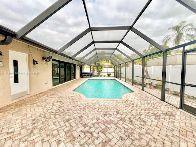 view of pool featuring a patio, glass enclosure, a fenced backyard, and a fenced in pool