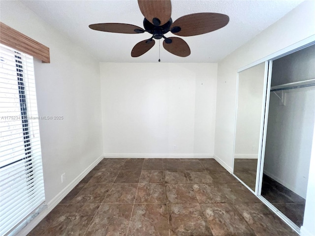 unfurnished bedroom featuring baseboards, a ceiling fan, and a closet