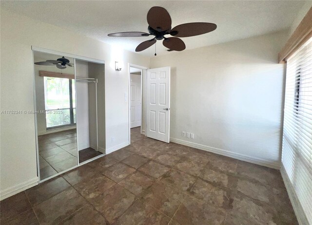unfurnished bedroom featuring baseboards, a closet, ceiling fan, and multiple windows