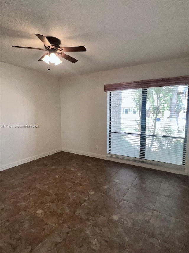spare room featuring a ceiling fan, baseboards, and a textured ceiling