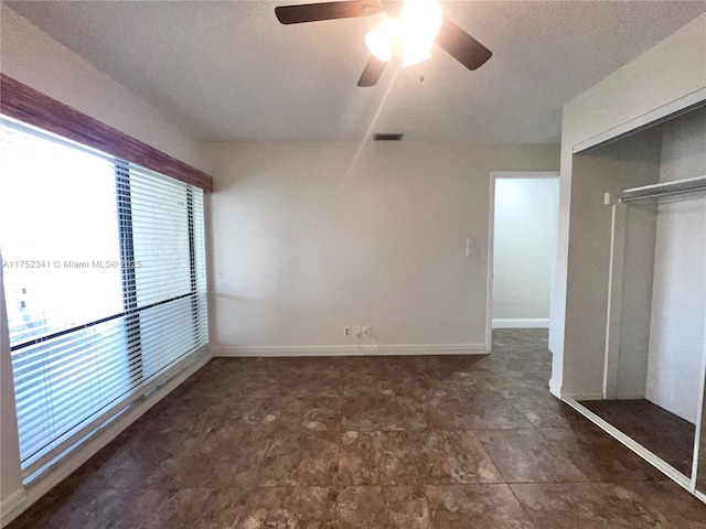 unfurnished room with baseboards, a ceiling fan, a textured ceiling, and visible vents