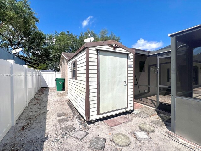 view of shed with a fenced backyard and a sunroom