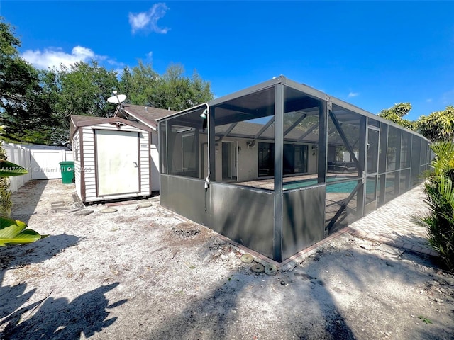 back of property featuring fence, an outdoor pool, a shed, an outbuilding, and a patio