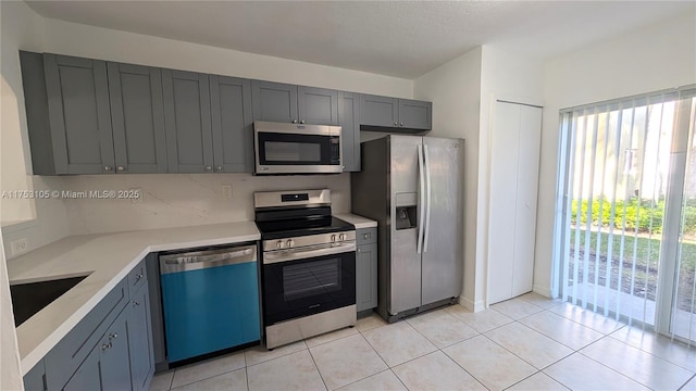 kitchen with light tile patterned floors, appliances with stainless steel finishes, light countertops, and a sink