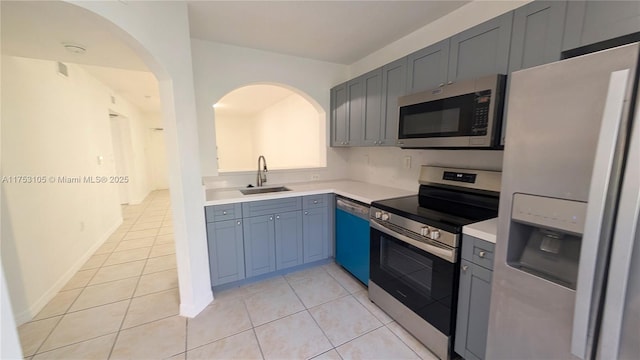 kitchen with light tile patterned floors, appliances with stainless steel finishes, light countertops, and a sink