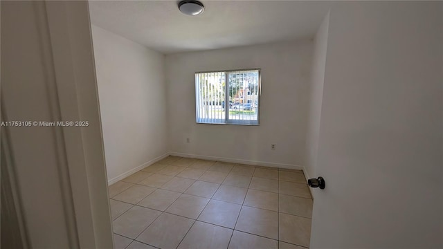 spare room featuring baseboards and light tile patterned floors