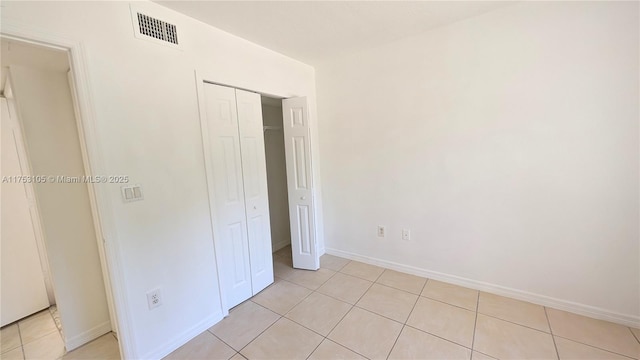 unfurnished bedroom with a closet, visible vents, baseboards, and light tile patterned floors