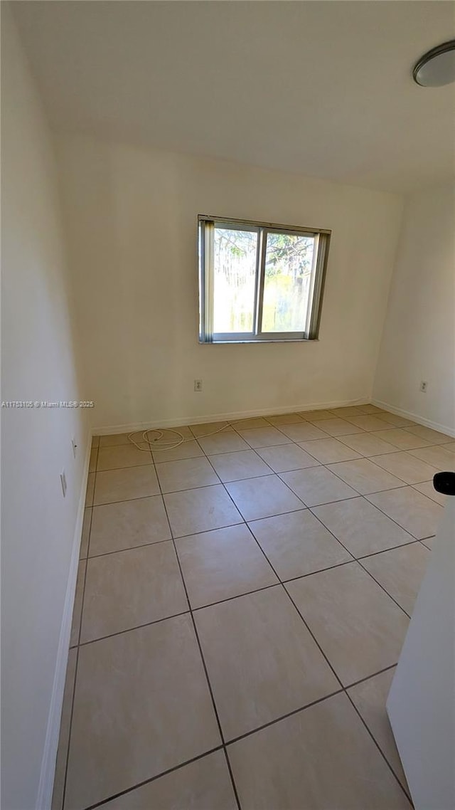 unfurnished room with light tile patterned floors and baseboards