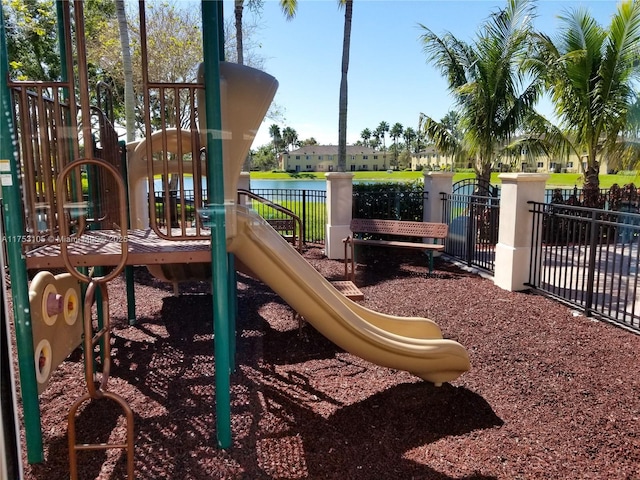 community jungle gym with a water view and fence