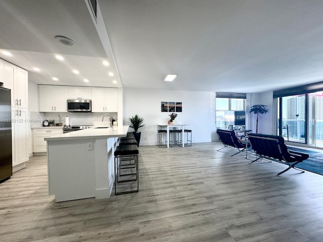 kitchen with a kitchen bar, appliances with stainless steel finishes, white cabinets, and wood finished floors