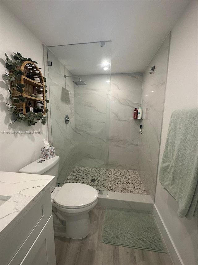 full bath featuring a marble finish shower, vanity, wood finished floors, and toilet